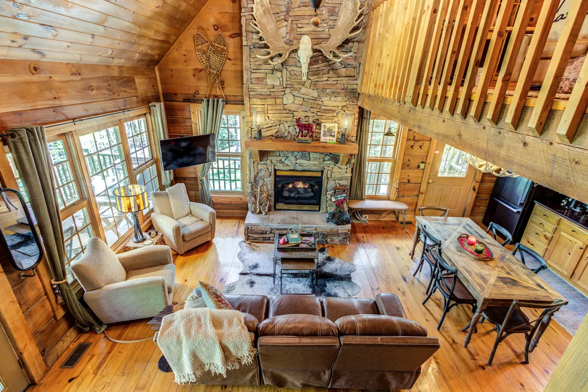 This interior shot highlights a cozy fireplace, sturdy wooden beams, a welcoming dining table, and a comfortable seating area—perfect for socializing, playing games, or winding down together.